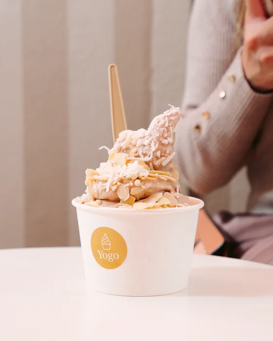 Vaso de helado de yogurt con almendra y coco en una mesa redonda